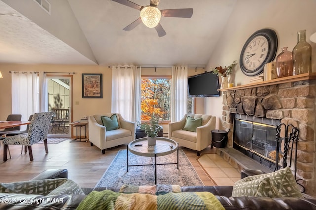 living area featuring ceiling fan, a fireplace, visible vents, and vaulted ceiling