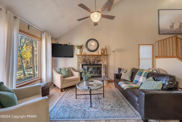 living area with a ceiling fan, a fireplace, high vaulted ceiling, and wood finished floors