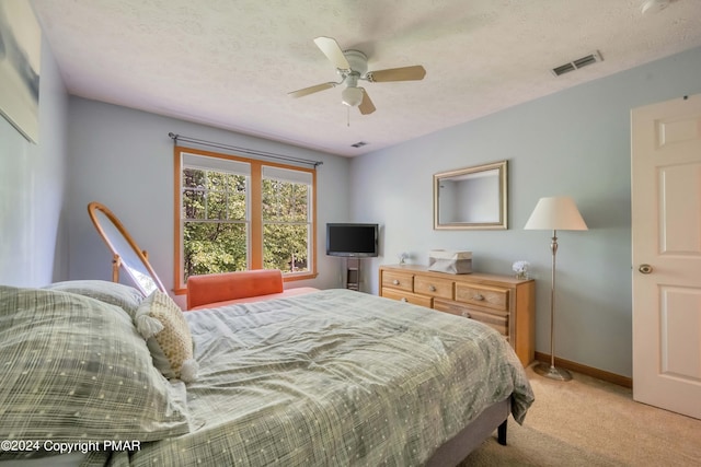 bedroom with a textured ceiling, light colored carpet, a ceiling fan, baseboards, and visible vents