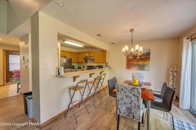 dining area featuring a chandelier, a textured ceiling, visible vents, baseboards, and light wood finished floors