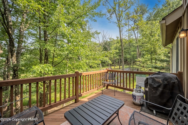 wooden terrace featuring a forest view and grilling area