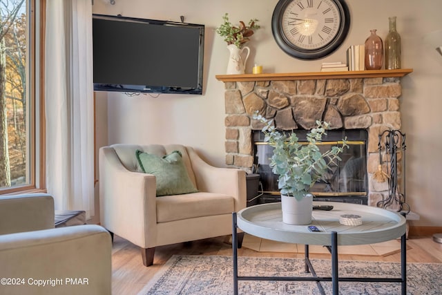 sitting room featuring plenty of natural light, a fireplace, baseboards, and wood finished floors