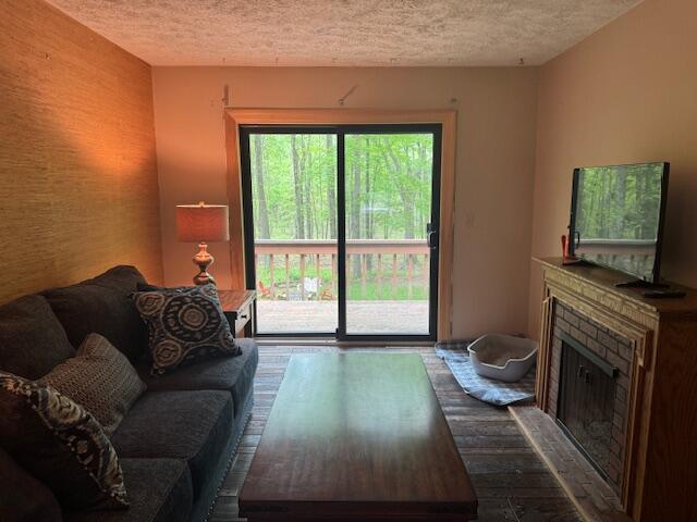 122 Sawmill Rd, Pocono Lake, PA 18347 - living area with a textured ceiling, a fireplace, dark wood finished floors, and an accent wall