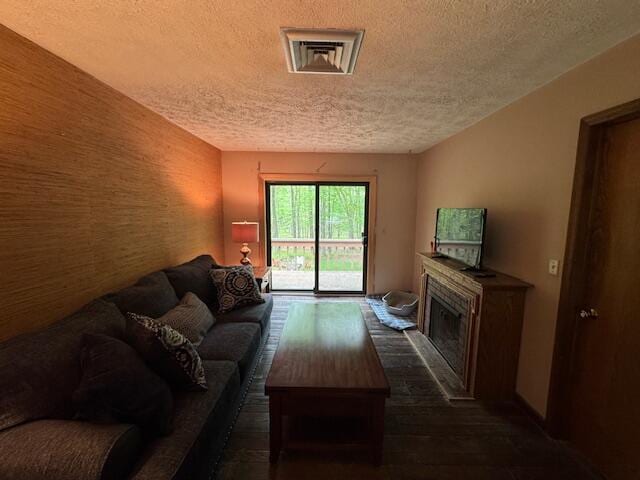 122 Sawmill Rd, Pocono Lake, PA 18347 - living room with a textured ceiling, a fireplace with raised hearth, an accent wall, and dark wood-style floors