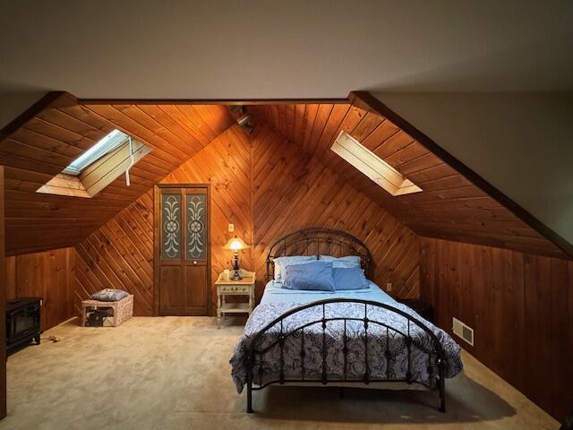 122 Sawmill Rd, Pocono Lake, PA 18347 - carpeted bedroom with a skylight, wooden walls, lofted ceiling, wood ceiling, and a wood stove