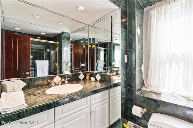 bathroom with toilet, a shower stall, vanity, and tile walls