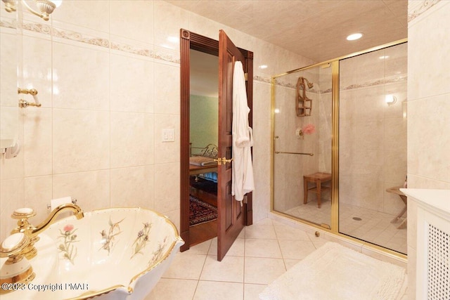 full bathroom with a freestanding bath, a stall shower, tile walls, and tile patterned floors