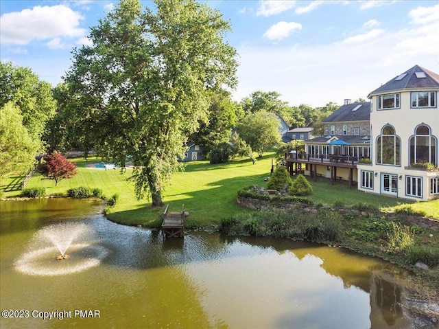 view of home's community with a lawn and a deck with water view