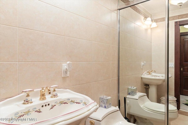 bathroom with a sink, toilet, and tile walls