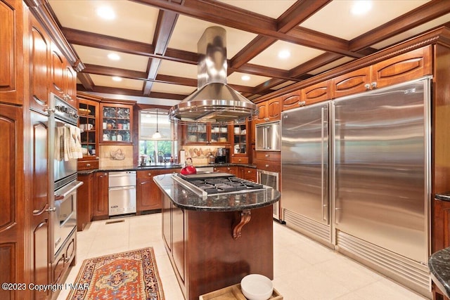 kitchen with a center island, stainless steel appliances, brown cabinetry, glass insert cabinets, and dark stone counters