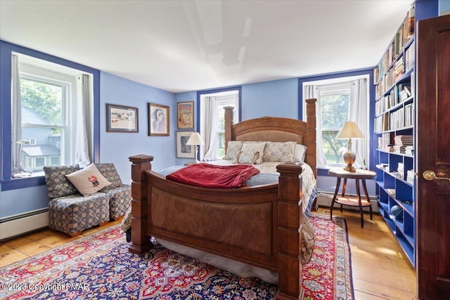 bedroom with a baseboard heating unit, a baseboard radiator, and light wood-style floors