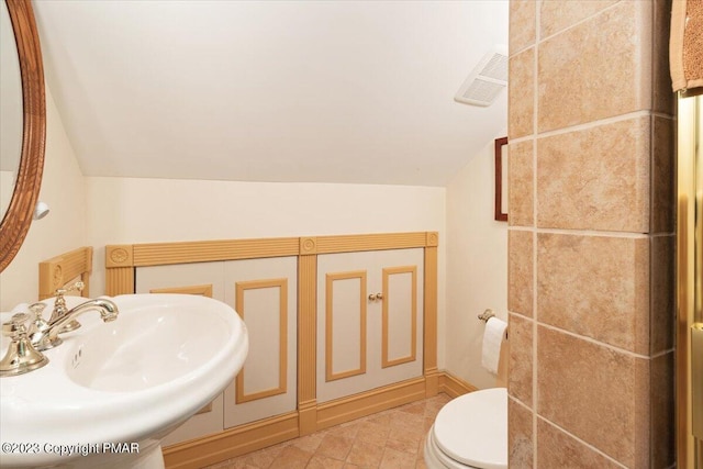 bathroom with toilet, a sink, visible vents, vaulted ceiling, and tile patterned floors