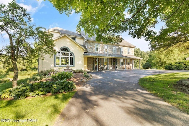 view of front of house with stone siding, aphalt driveway, and stucco siding