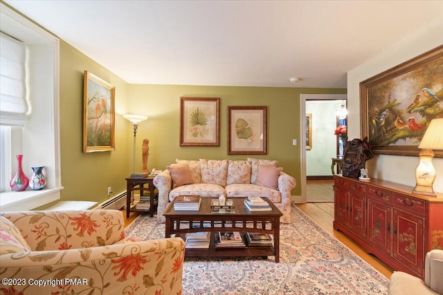 living room with baseboard heating, light wood-type flooring, and baseboards