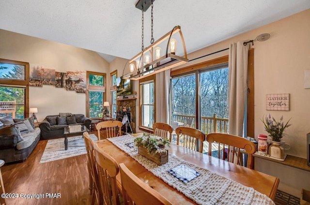 dining room with lofted ceiling, plenty of natural light, a fireplace, and wood finished floors