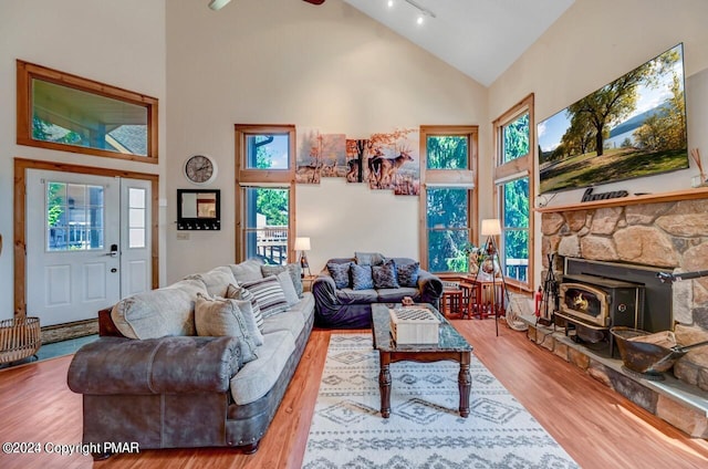 living room with high vaulted ceiling, a wood stove, rail lighting, and wood finished floors