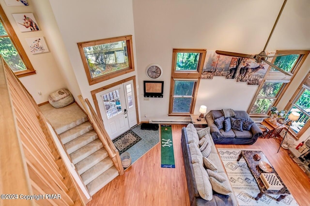 foyer featuring stairs, a ceiling fan, a towering ceiling, and wood finished floors