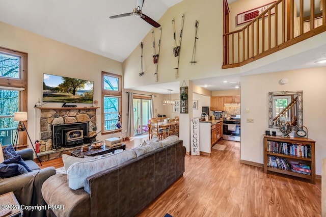 living area featuring a ceiling fan, a healthy amount of sunlight, high vaulted ceiling, and light wood finished floors