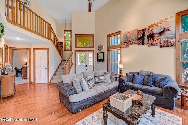 living area featuring light wood-style floors, stairway, and a high ceiling