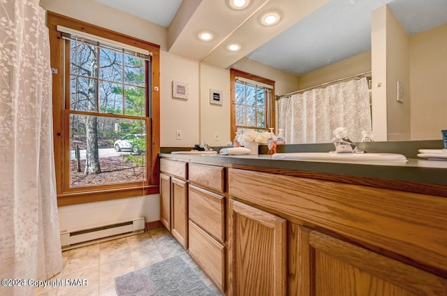 bathroom featuring a baseboard radiator, tile patterned flooring, recessed lighting, a sink, and double vanity