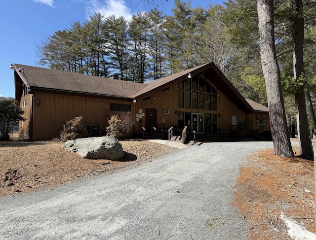 view of front of house with roof with shingles, central AC, and gravel driveway