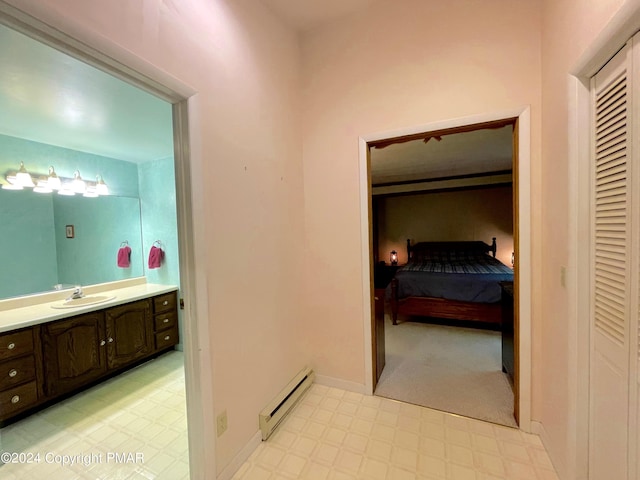 ensuite bathroom featuring a closet, vanity, baseboard heating, and tile patterned floors