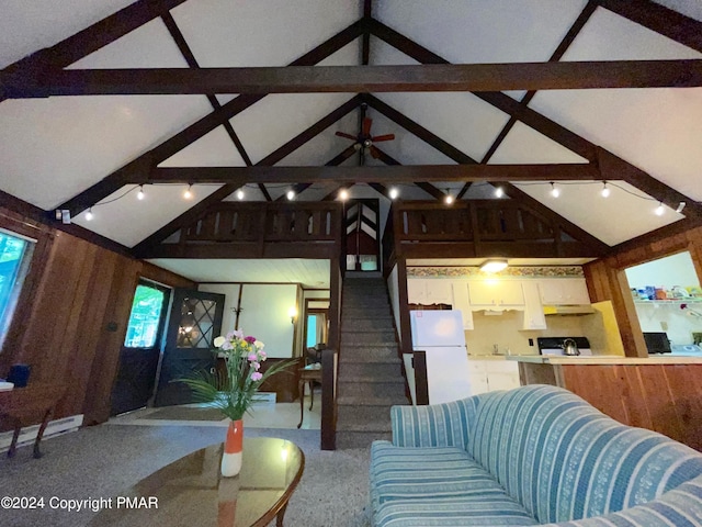 living area featuring a ceiling fan, vaulted ceiling with beams, wooden walls, and stairs