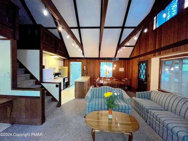 living room with vaulted ceiling with beams, rail lighting, stairs, and wooden walls