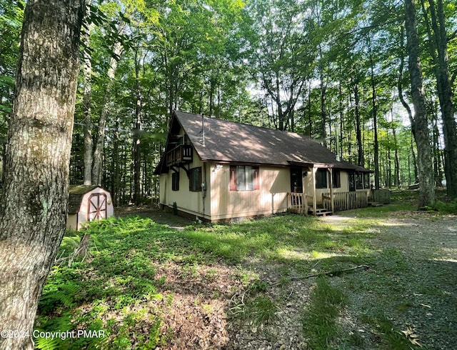 exterior space featuring a storage shed, roof with shingles, and an outbuilding