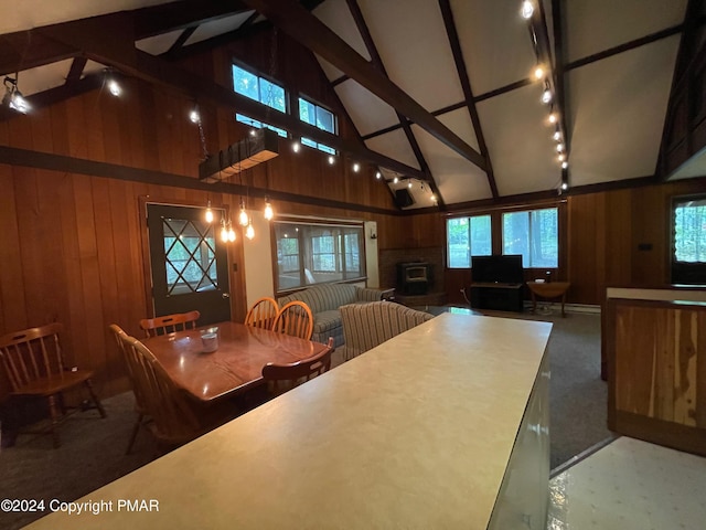 dining space with a brick fireplace, wooden walls, track lighting, high vaulted ceiling, and beamed ceiling