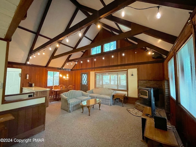 living room featuring a wood stove, wooden walls, and lofted ceiling with beams