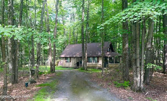 chalet / cabin with driveway and a view of trees