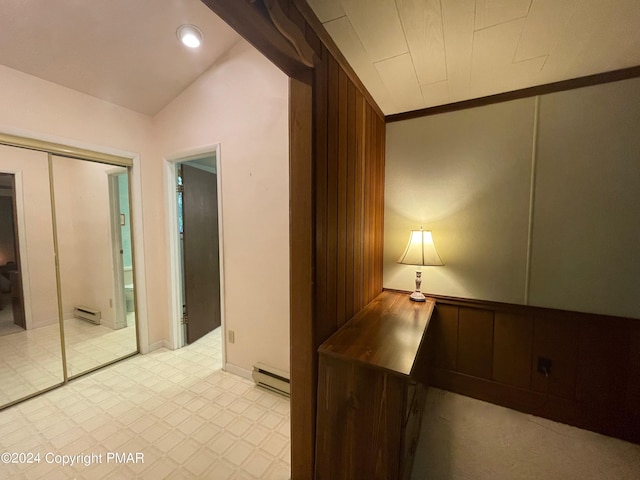 hallway with a baseboard heating unit, vaulted ceiling, and light floors