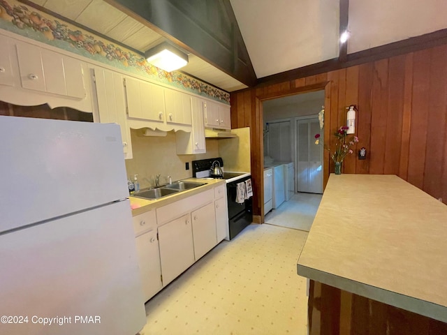 kitchen featuring electric range oven, light floors, freestanding refrigerator, wood walls, and a sink