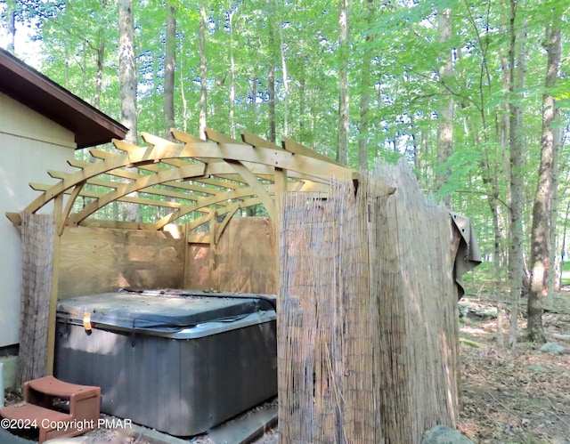 view of outbuilding featuring a hot tub and a pergola