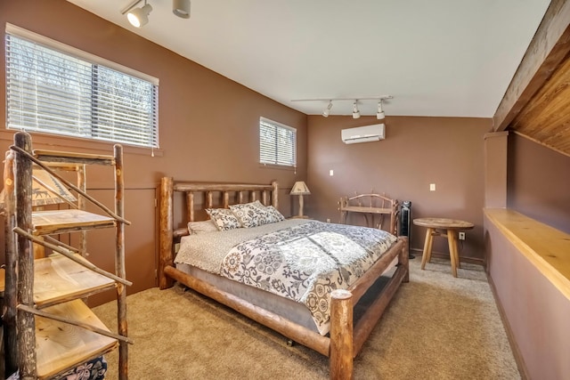 bedroom featuring a wall mounted air conditioner, carpet flooring, rail lighting, and baseboards