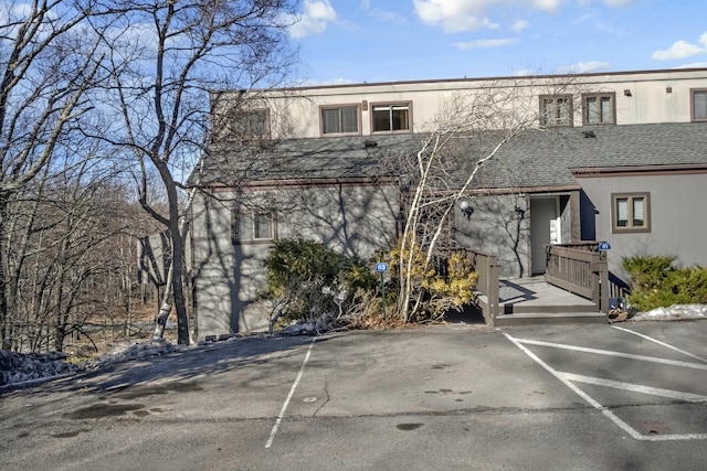 view of front of home featuring uncovered parking and roof with shingles