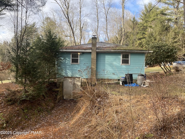 view of home's exterior with a chimney and a shingled roof