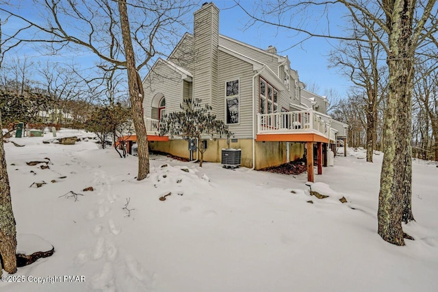 view of snow covered exterior featuring a chimney, a wooden deck, and central air condition unit