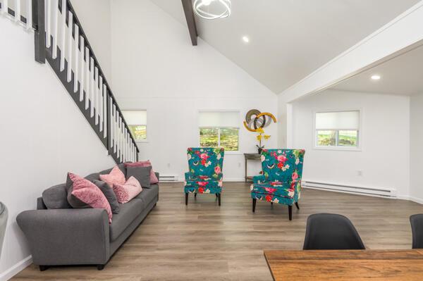117 Clifton Dr, Bushkill, PA 18324 - living area featuring a baseboard heating unit, beamed ceiling, stairway, plenty of natural light, and wood finished floors
