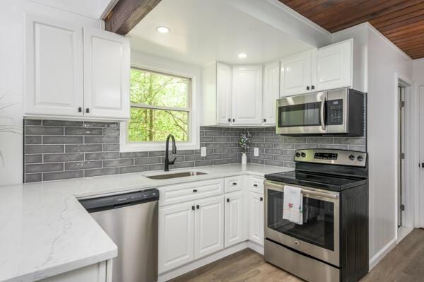 117 Clifton Dr, Bushkill, PA 18324 - kitchen with appliances with stainless steel finishes, a sink, light wood-style floors, white cabinetry, and wooden ceiling
