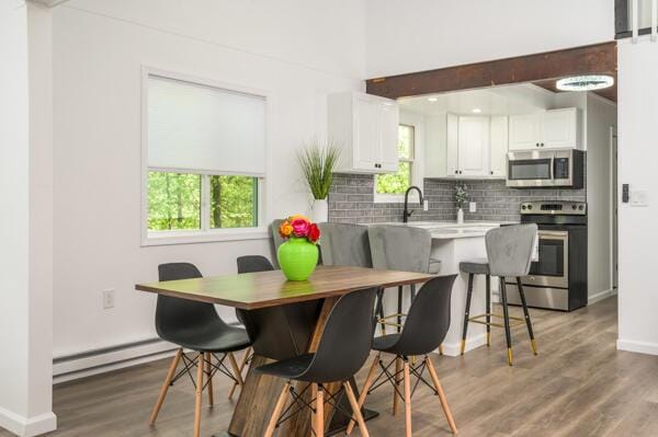 117 Clifton Dr, Bushkill, PA 18324 - dining space with a baseboard heating unit, plenty of natural light, wood finished floors, and baseboards