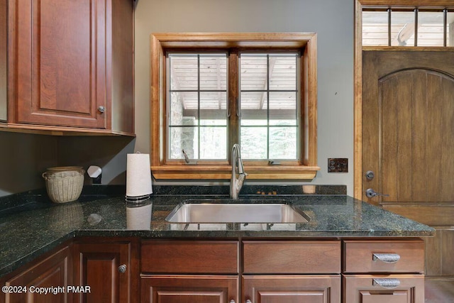 kitchen featuring dark stone counters and a sink