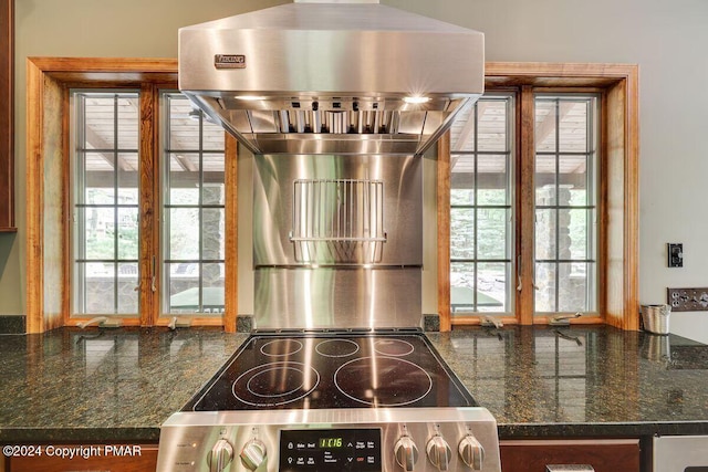 interior space featuring electric stove, plenty of natural light, and dark stone countertops