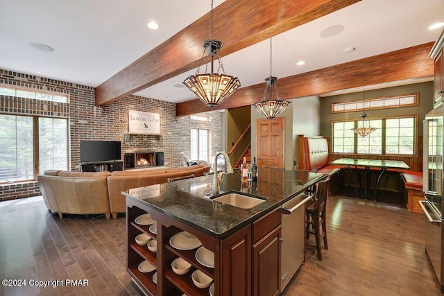 kitchen featuring dark wood finished floors, beamed ceiling, stainless steel dishwasher, open shelves, and a sink