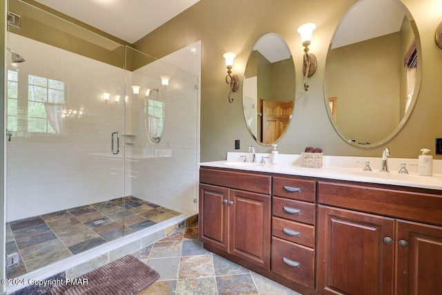 bathroom featuring double vanity, a stall shower, a sink, and stone finish floor