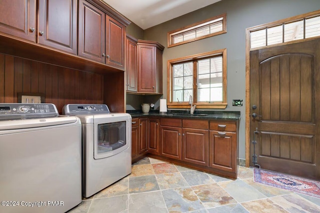 clothes washing area with cabinet space, washing machine and dryer, stone finish floor, and a sink