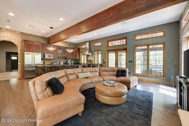 living area featuring light wood-style flooring, arched walkways, beam ceiling, and recessed lighting