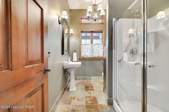 bathroom featuring toilet, a notable chandelier, baseboards, a stall shower, and stone tile flooring