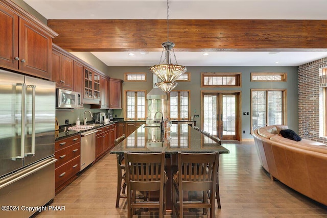 kitchen with a sink, appliances with stainless steel finishes, beamed ceiling, and a kitchen bar